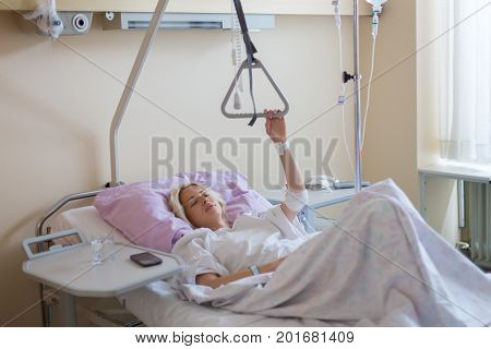 Bedridden female patient lying in hospital bed, recovering after surgery.