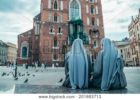 nun looking on old church in dramatic weather pigeons flying in clouds