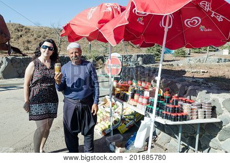 Golan Heights Israel August 27 2017 : The seller - druz stands with the customer and offers the goods near his shop with canned sweets in the parking lot on Mount Bental. on the Golan Heights in Israel.