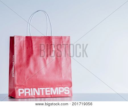 PARIS FRANCE - JUL 30 2017: Red paper clothes bag against studio background with the brand Printemps Sping Paris. Printemps is a French department store The Printemps stores focus on beauty lifestyle fashion accessories and men's wear