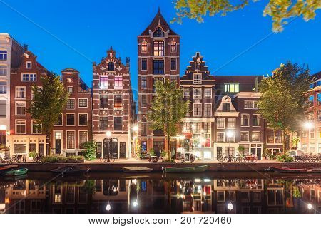 Amsterdam canal Herengracht with typical dutch houses and their reflections during morning blue hour, Holland, Netherlands.