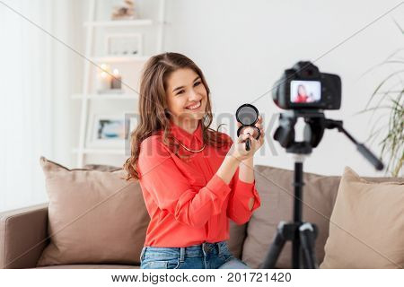blogging, technology, videoblog, makeup and people concept - happy smiling woman or beauty blogger with bronzer, brush and camera recording tutorial video at home