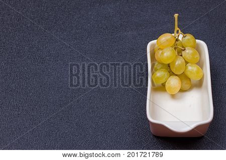 White grapes in a bowl on a black background.copy-space