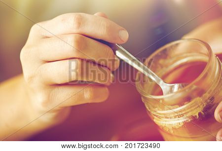healthy food, eating and ethnoscience concept - close up of woman hands with honey and spoon