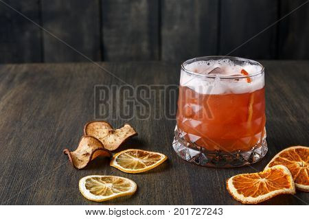 Cocktail on rustic wood background. Cold citrus alcohol beverage with tequila, blood orange juice and ginger beer, served with citrons and ice, copy space