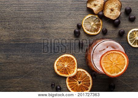 Cocktail on rustic wood background. Cold citrus alcohol beverage with tequila, blood orange juice and ginger beer, served with ice, citrons and chocolate snacks, top view, copy space