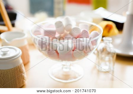 White and pink marshmellows in glass vase on dessert table selective focus