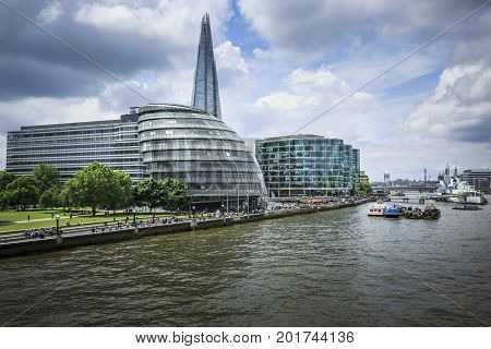 LONDON ENGLAND - JUNE 17 2016: Wide angle picture showing the City Hall The Shard PriceWaterhouseCoopers buildings a part of the River Thames with the HMS Belfast on the far right side of the picture . London.