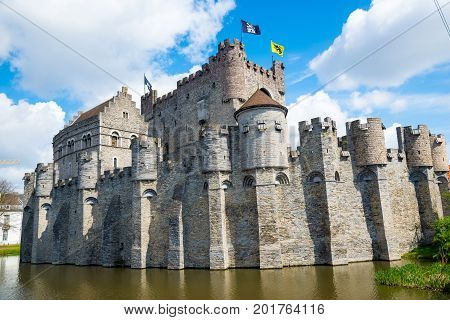 Medieval castle Gravensteen - Castle of the Counts with small windows surrounded by water in moat in Ghent, Flanders, Belgium.