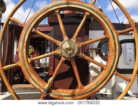 Close up of the helm of a yacht with the blue sky showing through the steering wheel. With space for text.