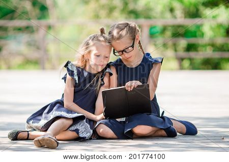 Adorable little school girls with notes and pencils outdoor.