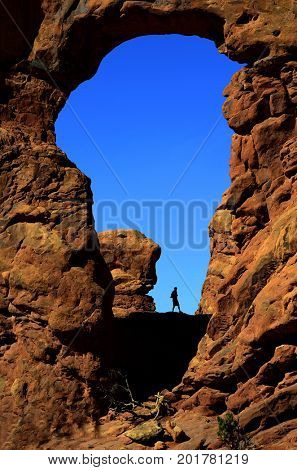 Silhouette of hiker in arch canyon rock formations