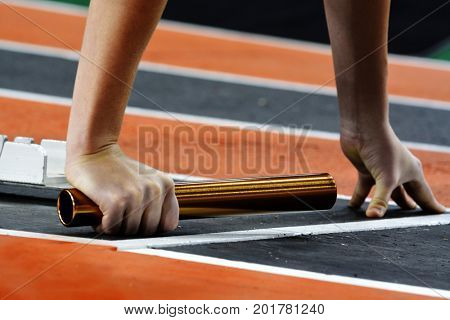 Runner running a race on track with baton relay for team score competition