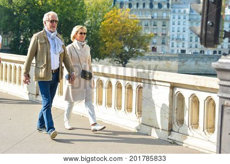 PARIS, FRANCE - OCTOBER 16, 2016: An elderly well dressed couple is walking and holding hands in a Paris, France.