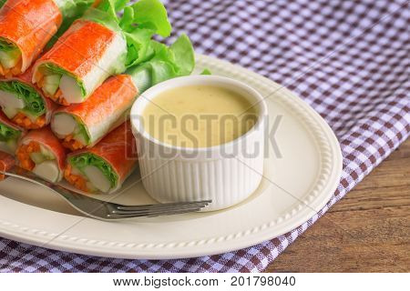 Fresh spring rolls with fresh vegetable and crab stick served with spicy salad cream dipping sauce. Rolls salad or fresh spring roll on white plate healthy delicious food for appetizer or meal. Fresh spring rolls in fusion food style.