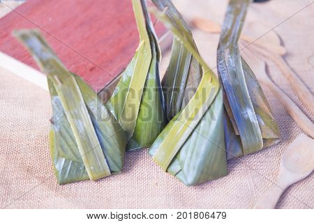Thai dessert made from steamed flour with filling inside wrapped with banana leaf it called 
