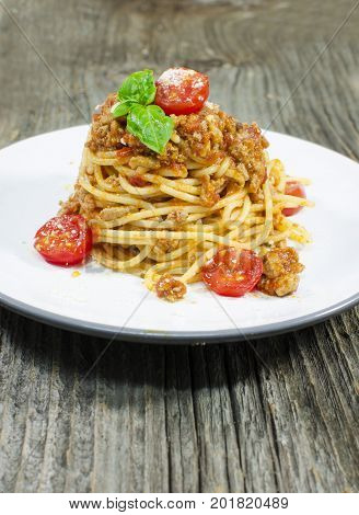 Italian spaghetti bolognese with tomato and basil on wood background