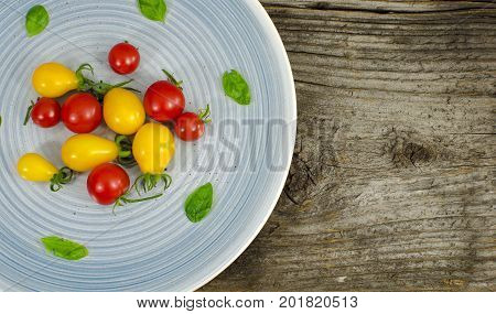 Cherry tomatoes on blue plate with basil
