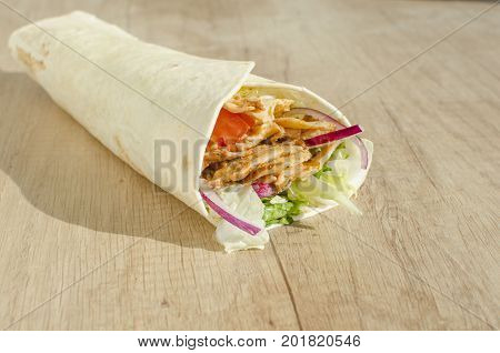 Doner kebab in a tortilla on wood table