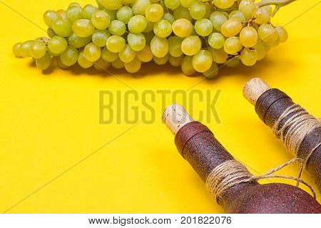 bottle of white wine with grapes on a yellowbackground