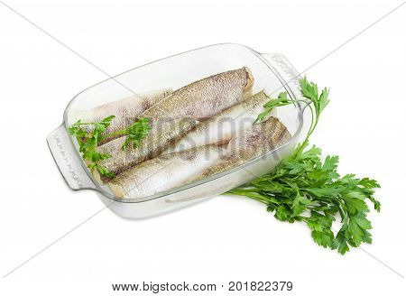 Several carcasses of the notothenia fish without of a heads and tails and with peeled scales and prepared for baking in the rectangular glass for baking and parsley on a white background