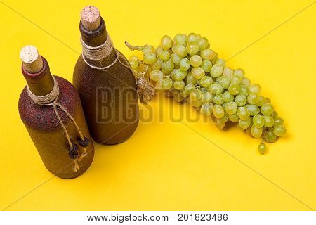 bottle of white wine with grapes on a yellowbackground