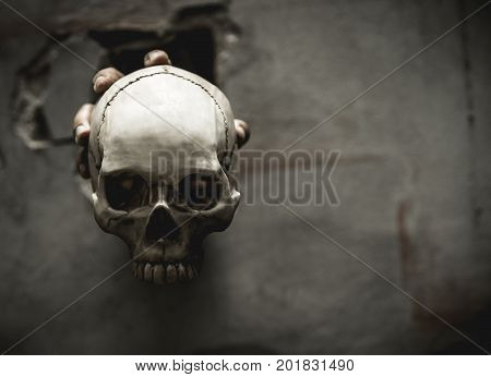 Skulls were held with the right hand of the man that emerges from the wall. Halloween Day element.