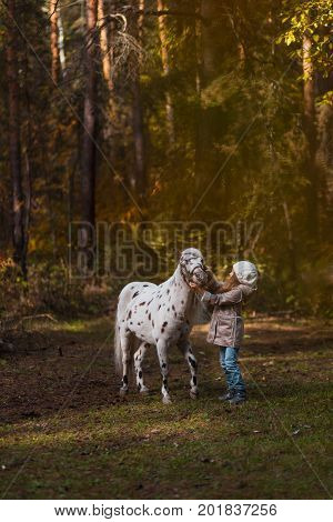 Little Cute Girl Walking With A Pony In The Autumn Forest