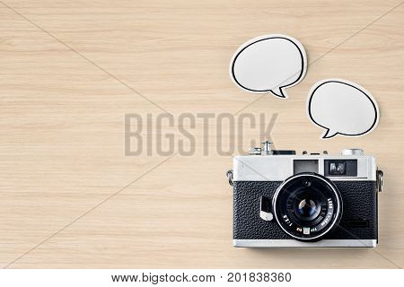 Business concept - Top view of modern office wood desktop background with blank bubble sticker and vintage camera for mockup design and copy space