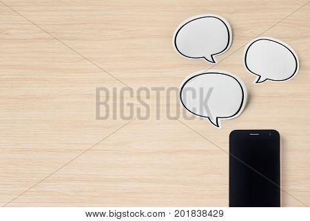 Business concept - Top view of modern office wood desktop background with blank bubble sticker and smart phone for mockup design and copy space