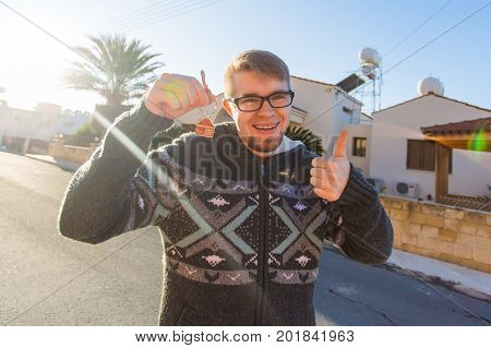Happy young man showing off the key to his new home. Owner, real estate and people concept.