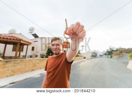 Happy young man showing off the key to his new home. Owner, real estate and people concept.