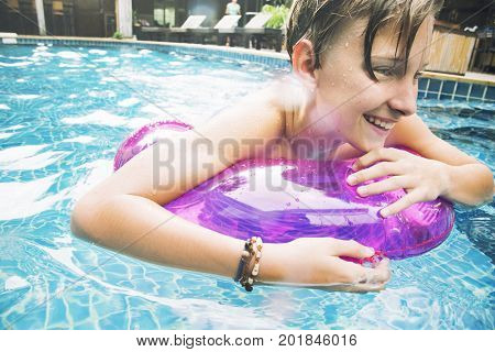 Young caucasian boy enjoying floating in the pool with tube