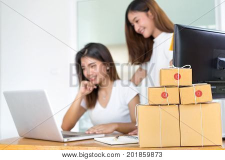 Young asian girl together teamwork freelancer small business private working at home office with laptop note phone packaging delivery online market on purchase checking orders to customer.