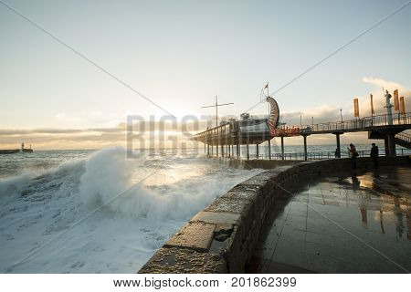 Storm at the sea and embankment street of Yalta city in Crimea in the morning on 24.10.2016. Big waves and tides wash against with lots of splashes.