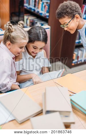 funny little kids reading book in library