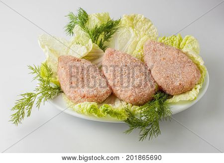 Raw Semifinished Cutlet With Greens On A Plate. Isolated