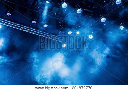 Blue light rays from the spotlight through the smoke at the theater or concert hall. Lighting equipment for a performance or show.