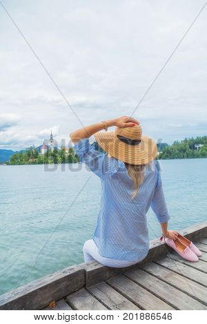 Young woman sitting on a wooden pier and enjoying the summertime.