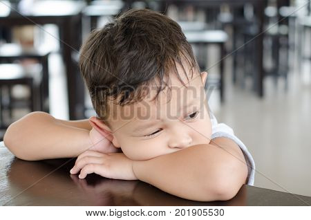 Boy about 4-5 years old seat alone in library with very sadness and thinking something and same like waiting some one.
