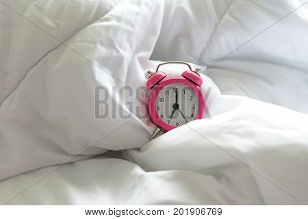Pink Alarm clock get up six o'clock on bed in morning with sun light. Lifestyle Concept