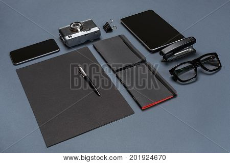 A set of black office accessories, glasses, old camera and tablet on gray background. Flat lay. Still life. Mock-up