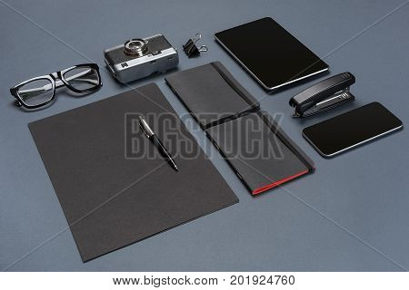 A set of black office accessories, glasses, old camera and tablet on gray background. Flat lay. Still life. Mock-up