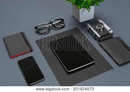 A set of black office accessories, glasses, green flower and smart on gray background. Flat lay. Still life. Mock-up