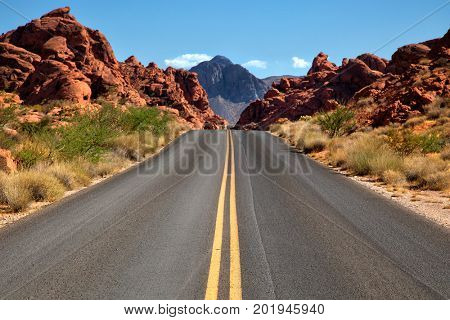 Straigh road into Valley of fire in Nevada with mountains in background