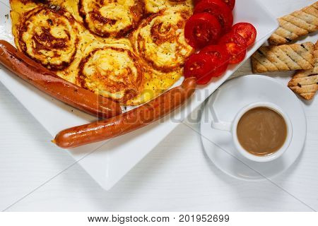 Breakfast of an omelette with sausages and coffee on a white wooden background