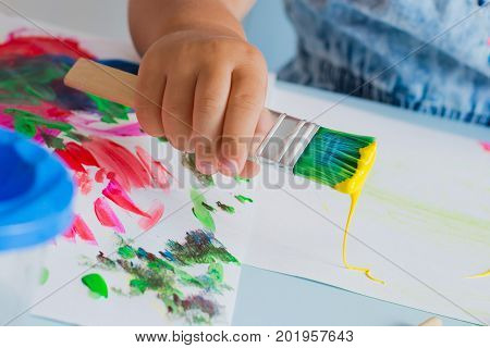 Brush with paint in the child's hand. Close-up