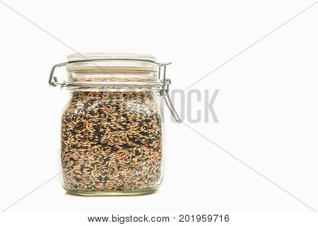 Glass jar with Mixed bird seed. Jar with a steel lock on a white background