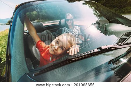I'm so like travel with my mom! Little boy makes funny faces through windshield in cabriolet car