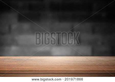 Wood table on blurred concrete block wall background.